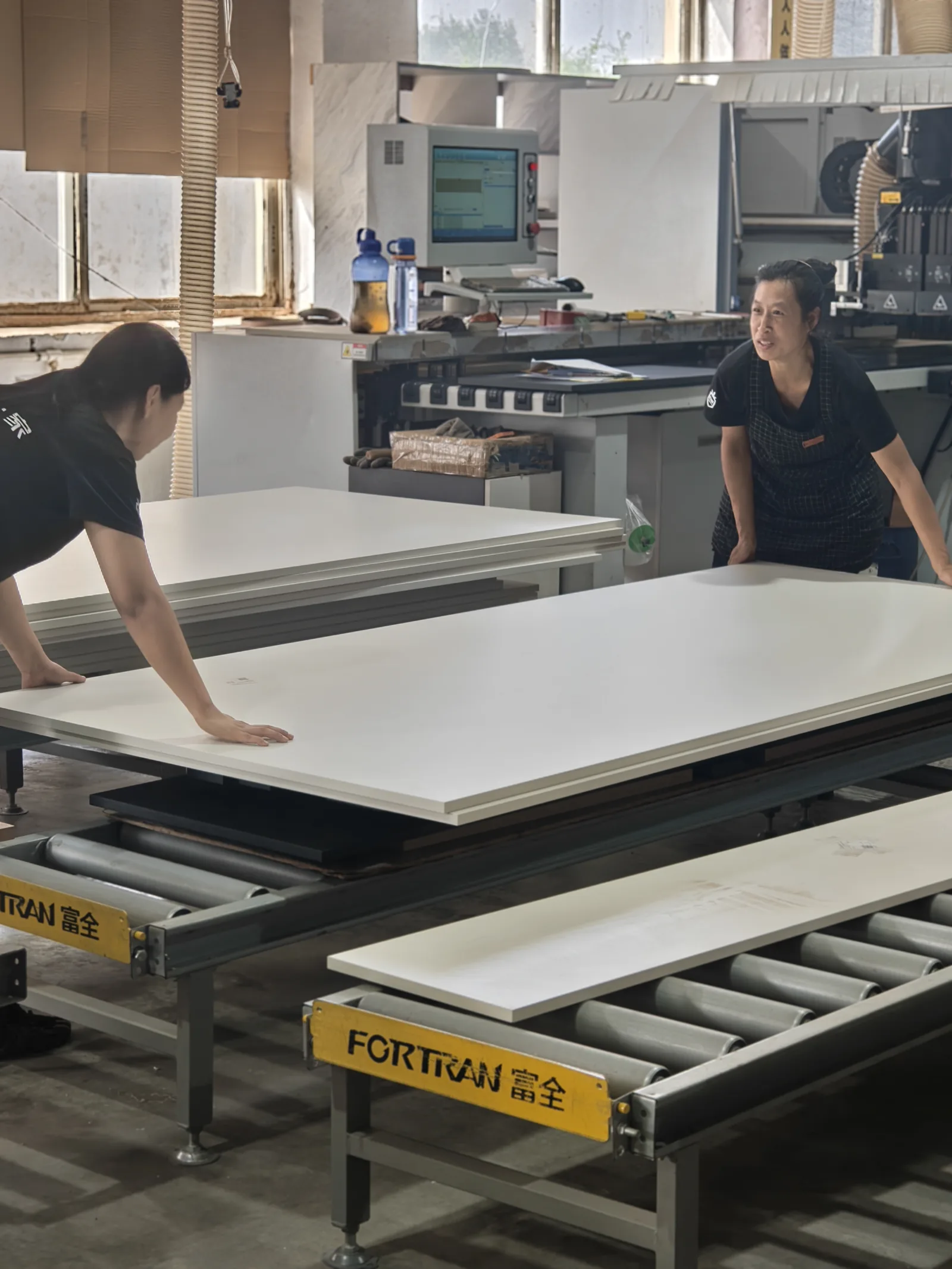 SNEJ team handling panels beside production equipment
