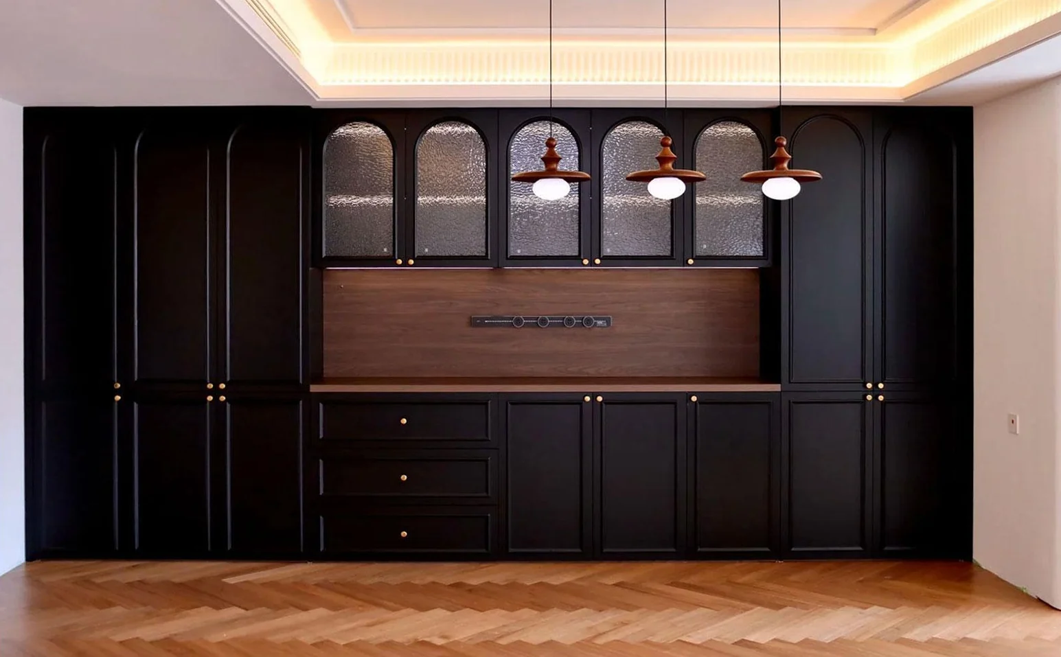 Dark dining cabinetry with arched glazed upper doors and a wood-toned recess