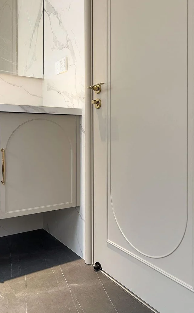 Curved moulding on an open pale door beside a bathroom vanity
