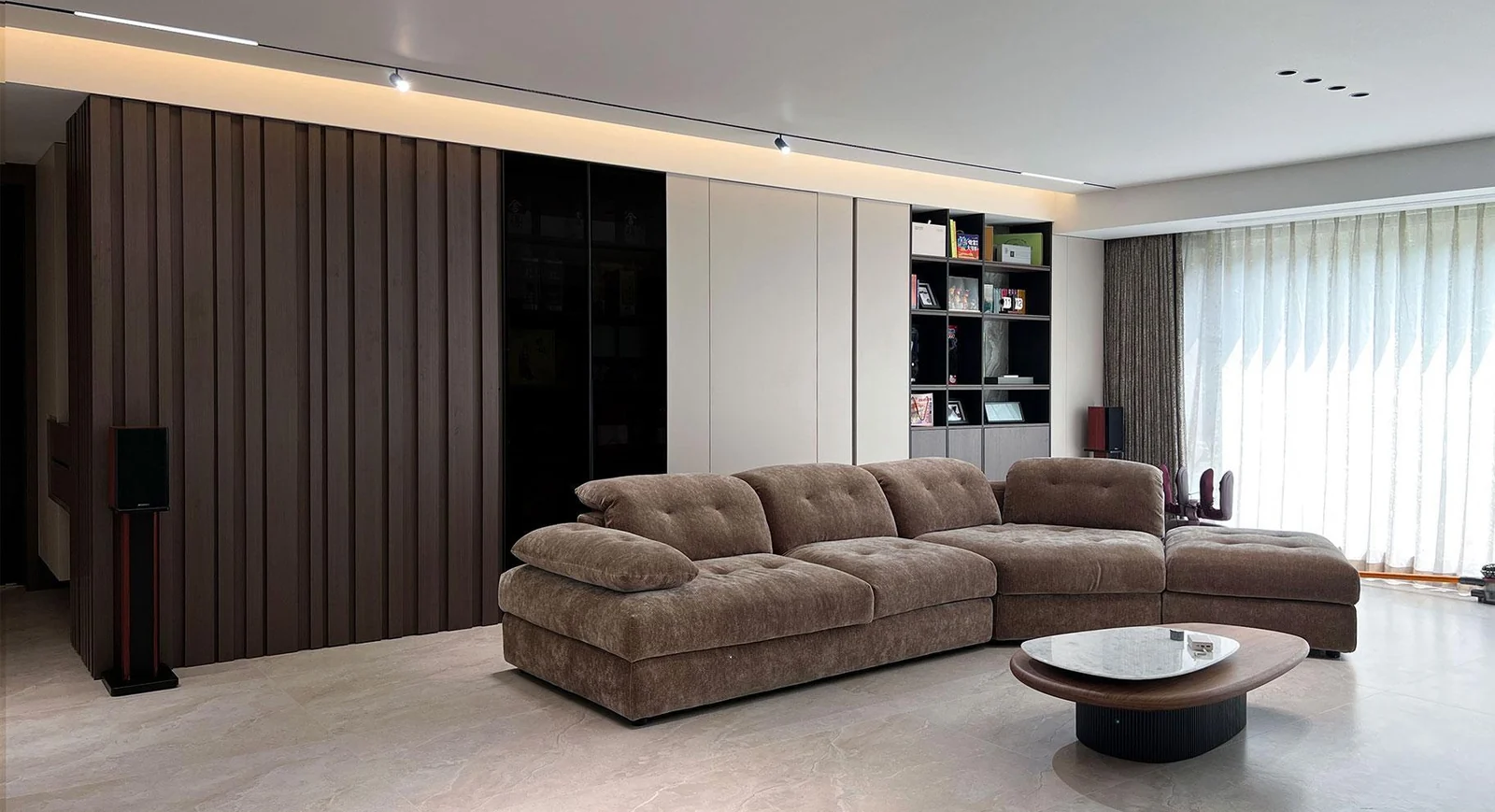 Living room with a brown sofa, vertically panelled wall and fitted display storage
