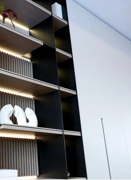Illuminated display shelves beside a pale tall cabinet front