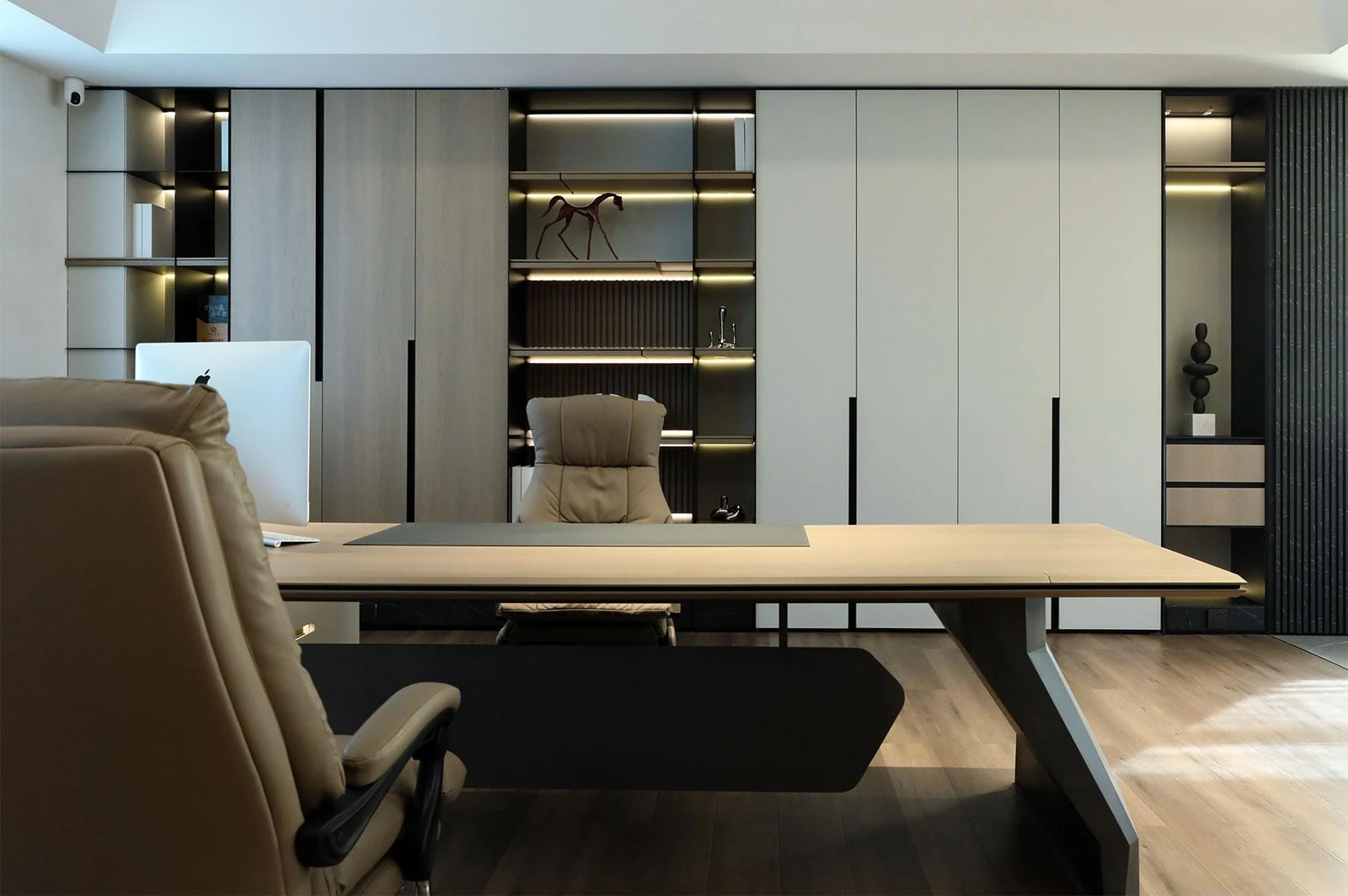 Study with pale fitted cabinets, dark open shelves and a broad desk